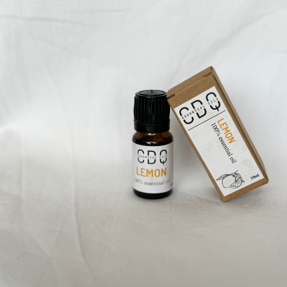 CDQ Lemon Essential Oil bottle with fresh lemons, pure citrus aroma, ideal for aromatherapy, natural cleaning, and skincare.